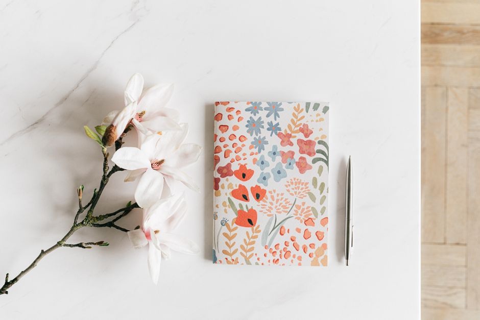 A notebook and book arranged beside a delicate branch in soft natural light.